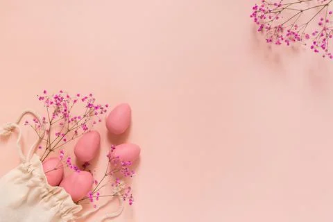 Easter composition with pink eggs and flowers arranged near bag Stock Photos