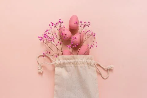 Easter composition with pink eggs and flowers arranged near bag 库存照片