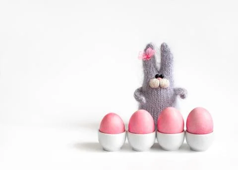 Easter composition with pink eggs in stands and a fluffy knitted rabbit  Stock Photos