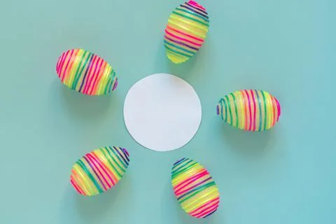 Easter composition with rainbow striped eggs placed around white circle frame Stock Photos