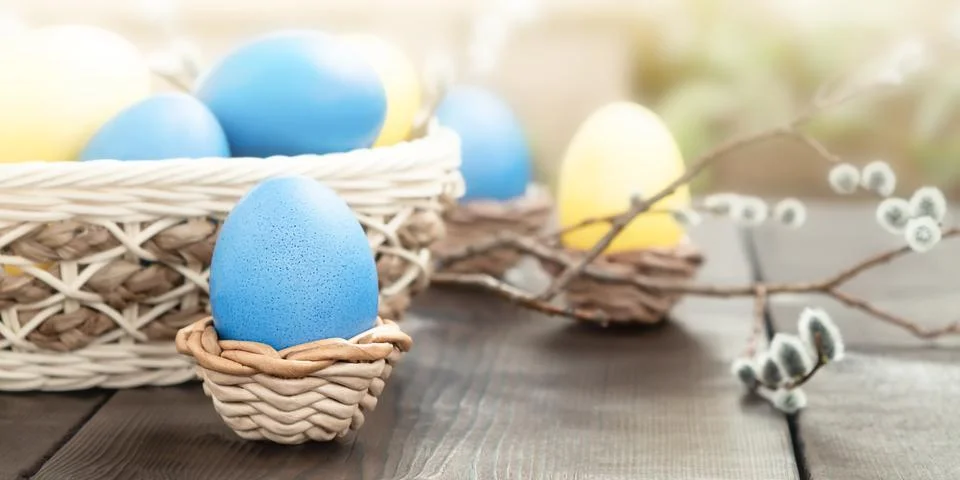 Easter composition - several colored eggs in a basket and on a dark wooden ta Stock Photos