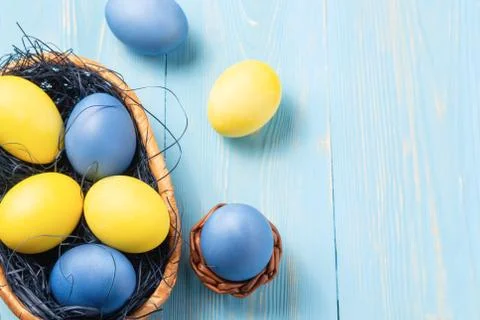 Easter composition - several colored eggs in a basket on a blue wooden table, Stock Photos