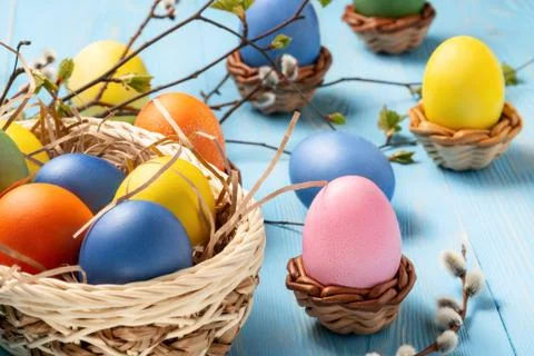 Easter composition - several colored eggs in a basket on a blue wooden table  Stock Photos