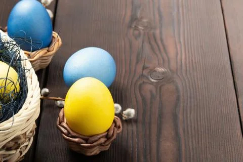 Easter composition - several colored eggs in a basket and on a dark wooden ta Stock Photos