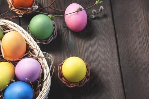 Easter composition - several colored eggs in a basket and on a dark wooden ta Stock Photos