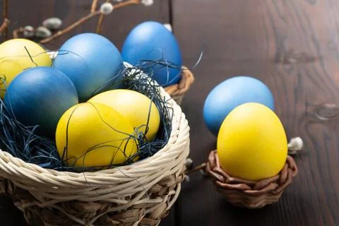 Easter composition - several colored eggs in a basket and on a dark wooden ta Stock Photos