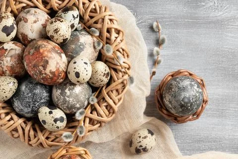 Easter composition - several marble eggs painted with natural dyes in a wicke Stock Photos