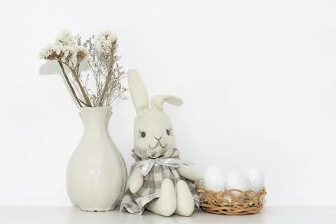 Easter composition with a soft rabbit igushka, white eggs in a basket and a v Stock Photos
