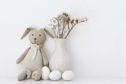 Easter composition with a soft rabbit igushka, white eggs in a basket and a v Stock Photos
