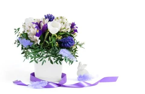 Easter composition. Spring flowers with feathers, purple ribbon  Stock Photos