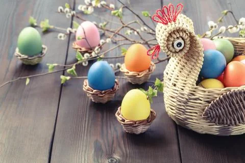 Easter composition - a wicker basket in the form of a chicken with colored eg Stock Photos