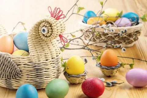 Easter composition - a wicker basket in the form of a chicken with colored eg Stock Photos