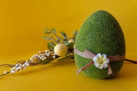Easter composition on a yellow background. Green Easter egg and a branch with Stock Photos