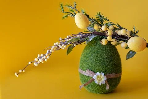 Easter composition on a yellow background. Green Easter egg and a branch with Stock Photos