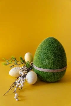 Easter composition on a yellow background. Green Easter egg and a branch with Stock Photos