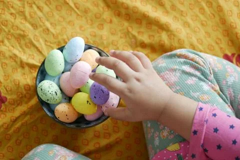 Easter concept with child hand pick colorful egg on pink background. Stock Photos