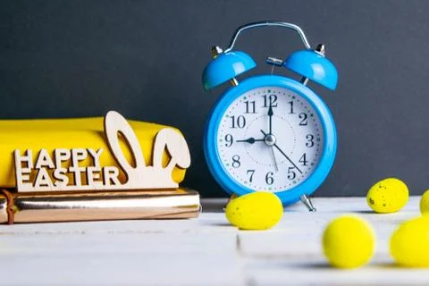 Easter concept, clock and apple, yellow books, eggs are scattered next to the Stock Photos