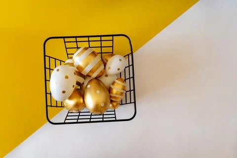 Easter concept. Easter eggs in a basket on a yellow and white background with Stock Photos