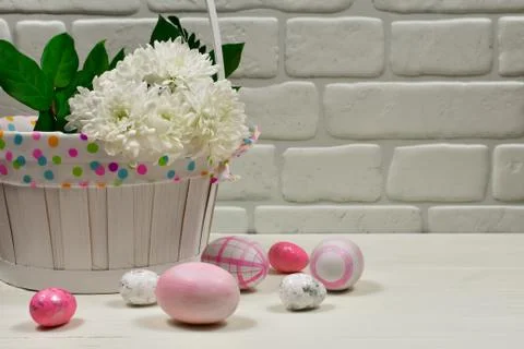 Easter concept. Easter pink eggs near a basket with white flowers on a wooden Stock Photos