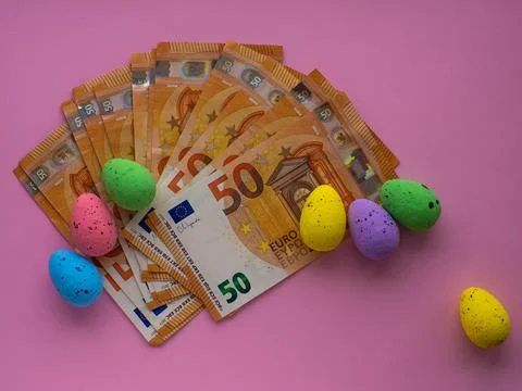 Easter concept with Euro banknotes and colorful eggs on pink background. Stock Photos