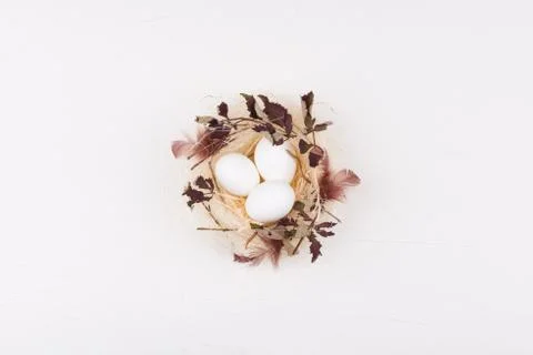 Easter concept. Flat lay of white eggs in stylish straw nest Stock Photos