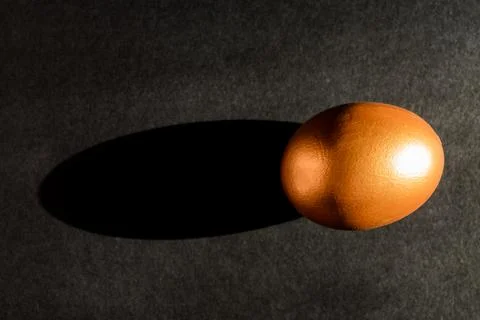Easter concept. A golden egg on black background with shadow light. Stock Photos