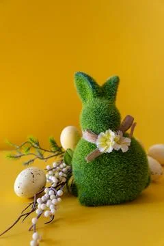 Easter concept. Green Easter bunny with a branch with Easter eggs on a yellow Stock Photos