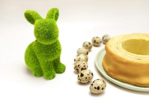 Easter concept. Green hare, rabbit with quail eggs and delicious baumkuchen Stock Photos