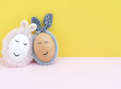 Easter concept. Two creative white and brown Easter eggs with bunny ears and Stock Photos