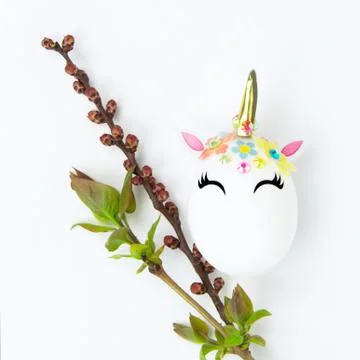 Easter concept. Unicorn shaped egg. And twigs with buds and blooming leaves Stock Photos