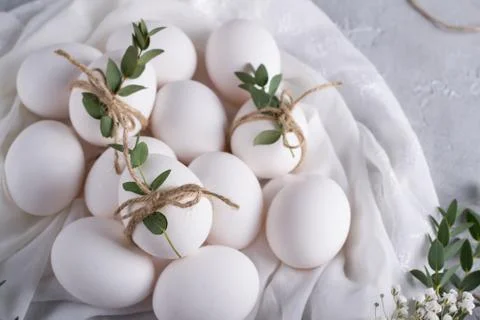 Easter concept. White chicken eggs on white fabric. Decorated with eucalyptus Stock Photos