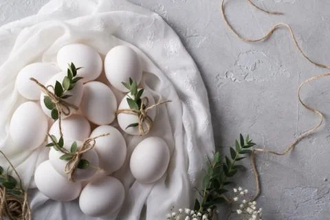 Easter concept. White chicken eggs on white fabric. Decorated with eucalyptus Stock Photos