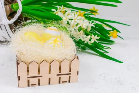 Easter concept. Yellow Easter eggs in a nest next to a bouquet of daffodils on a Stock Photos