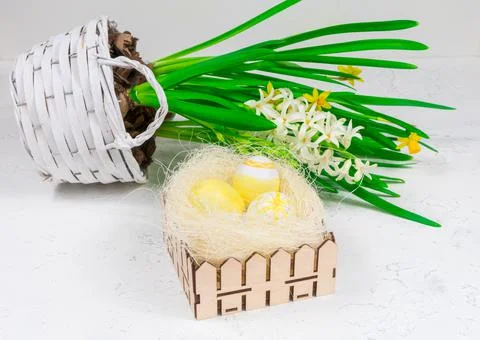 Easter concept. Yellow Easter eggs in a basket next to a bouquet of daffodils on Stock Photos
