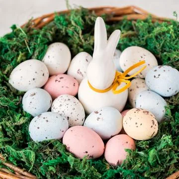 Easter concept.bunny in a basket with easter colored eggs. Stock Photos