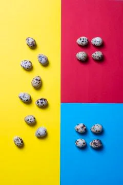 Easter creative concept. Chicken quail eggs on a yellow, red and blue backgro Stock Photos