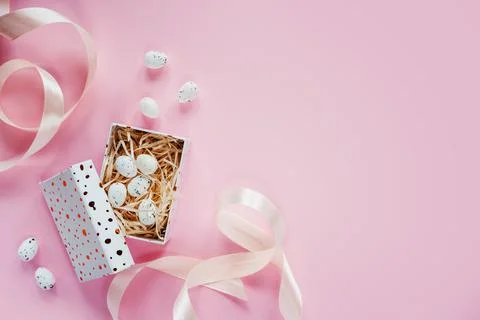 Easter creative layout with Easter eggs in a gift box with pink ribbons on pink Stock Photos