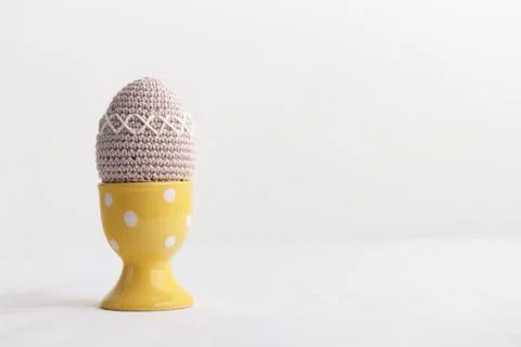 Easter crocheted egg in a yellow egg holder on white background 库存照片
