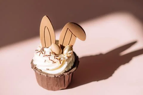 Easter cupcake with rabbit ears on pink background under hard light Stock Photos