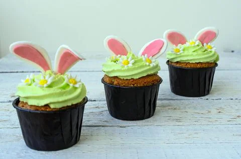 Easter cupcake with whipped green cream. Bunny ears stick out and daisies. Stock Photos