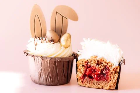 Easter cupcakes with rabbit ears, one cut with berry filling on a pink back.. Stock Photos