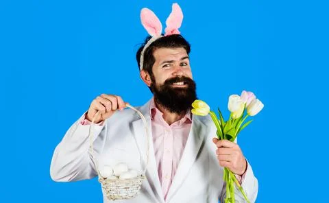 Easter day. Egg hunt. Smiling bearded man with basket eggs and tulips. Bunny  Stock Photos