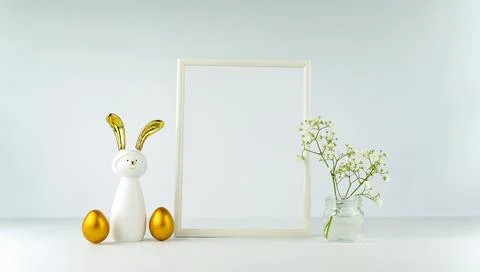 Easter decor on the background of a white table and wall. Eggs and a rabbit w Stock Photos