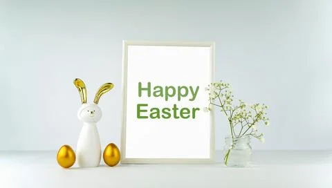 Easter decor on the background of a white table and wall. Eggs and a rabbit w Stock Photos
