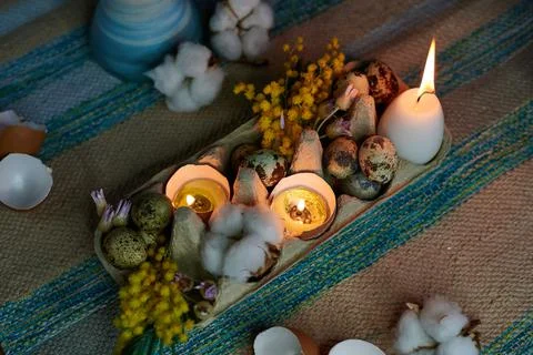 Easter decor in an egg box with burning candles and dried flowers Stock Photos