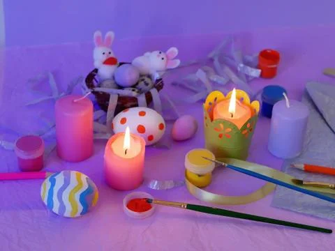 Easter decor, painted eggs, paints, brushes, lighted pink candles Stock Photos