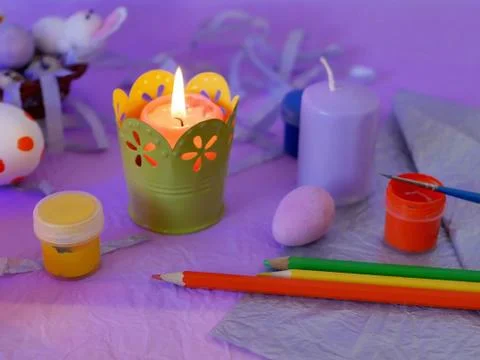 Easter decor, painted eggs, paints, brushes, lighted pink candles Stock Photos