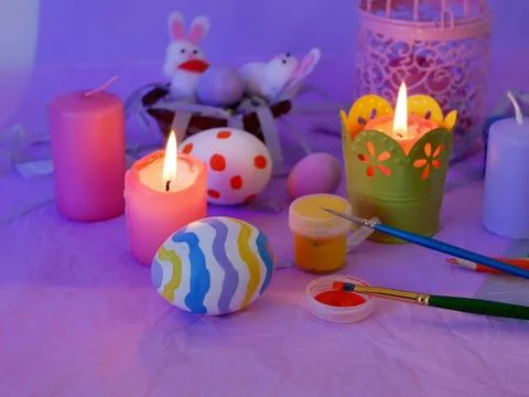 Easter decor, painted eggs, paints, brushes, lighted pink candles Stock Photos
