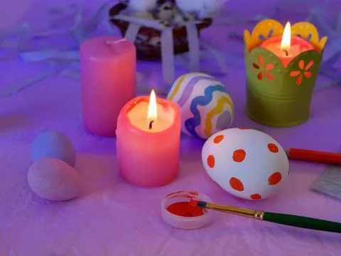 Easter decor, painted eggs, paints, brushes, lighted pink candles Stock Photos