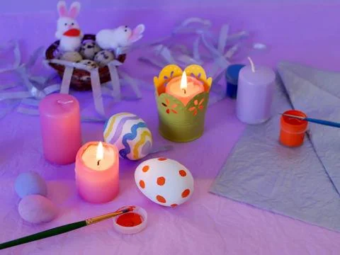 Easter decor, painted eggs, paints, brushes, lighted pink candles 库存照片